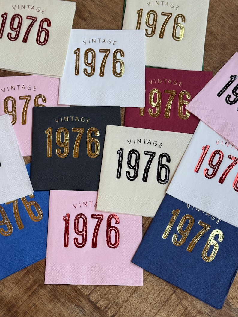 May include: A collection of square paper napkins in various colors, each printed with the word "VINTAGE" above the number "1976". The numbers are in gold, red, and black, with a variety of background colors.