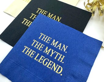 May include: Three paper napkins with gold foil lettering. The napkins are in blue, black, and beige. The text on the napkins reads "The Man. The Myth. The Legend."