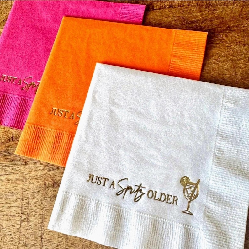 Cocktail Napkins that read Just A Spritz Older, with an Aperol Spritz.  Spritz themed Foil Stamped Napkins