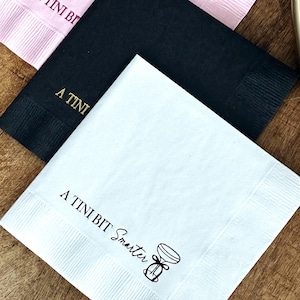Könnte beinhalten: Drei Papierservietten mit dem Aufdruck "A Tin Bit Smarter". Die Servietten sind in rosa, schwarz und weiß.