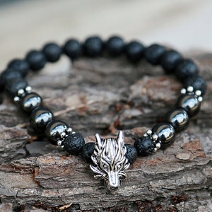 Pode incluir: Uma pulseira de contas pretas com um pingente de cabe&ccedil;a de lobo prateado. A pulseira &eacute; feita de contas de rocha vulc&acirc;nica preta e contas met&aacute;licas. O pingente de cabe&ccedil;a de lobo &eacute; detalhado e adiciona um toque &uacute;nico ao acess&oacute;rio.