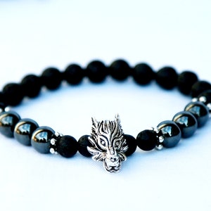 Pode incluir: Pulseira de contas pretas com um pingente de cabe&ccedil;a de lobo prateada. A pulseira apresenta uma mistura de contas pretas foscas e brilhantes. O pingente de cabe&ccedil;a de lobo &eacute; detalhado e adiciona um elemento &uacute;nico.