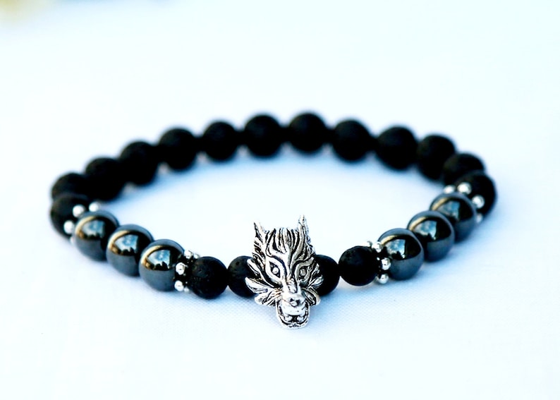 Pode incluir: Pulseira de contas pretas com um pingente de cabe&ccedil;a de lobo prateada. A pulseira apresenta uma mistura de contas pretas foscas e brilhantes. O pingente de cabe&ccedil;a de lobo &eacute; detalhado e adiciona um elemento &uacute;nico.