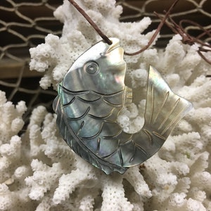 May include: A silver iridescent fish pendant carved from mother of pearl with a brown cord.
