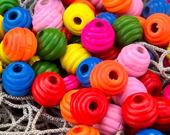 May include: A collection of colorful wooden beads in various shades of red, blue, green, yellow, pink, and orange. The beads are arranged in a random pattern and are all approximately the same size.