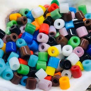May include: A collection of colorful glass beads in various shapes and sizes. The beads are a mix of opaque and translucent colors, including blue, green, red, yellow, brown, and white.