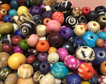 May include: A collection of colorful wooden beads in various shapes and sizes. The beads are made of natural wood and have a variety of patterns and designs.