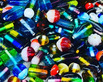 May include: A collection of colorful glass beads in various shapes and sizes. The beads are a mix of blue, green, red, yellow, and white.