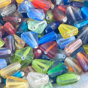 May include: A collection of colorful glass triangle beads. The beads are translucent and have a variety of colors, including blue, green, yellow, red, and purple.