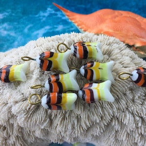 May include: Eight small glass fish charms with orange, black, white, and yellow stripes. Each charm has a gold loop for hanging.