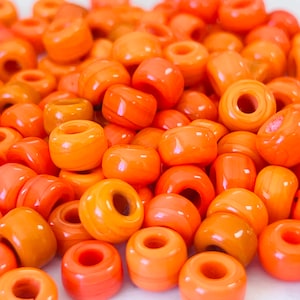 May include: A large pile of orange and yellow plastic beads. The beads are round and have a hole in the center. They are perfect for making jewelry or other crafts.