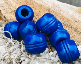 Puede incluir: Un conjunto de cuentas de madera azul vibrante. Cada cuenta es cilíndrica con una ranura en el centro. Las cuentas están dispuestas sobre una red blanca, sugiriendo un tema náutico o artesanal.