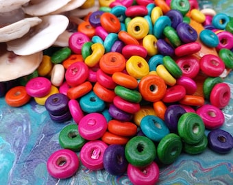 May include: A large pile of colorful wooden beads in various shades of pink, purple, green, blue, yellow, and orange. The beads are all round and have a hole in the center.