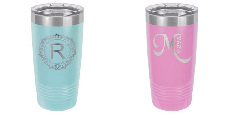 May include: Two insulated tumblers. One is light blue with a silver lid and a decorative silver letter "R" inside a circular design. The other is pink with a silver lid and the silver letter "M" with the name "Maria".