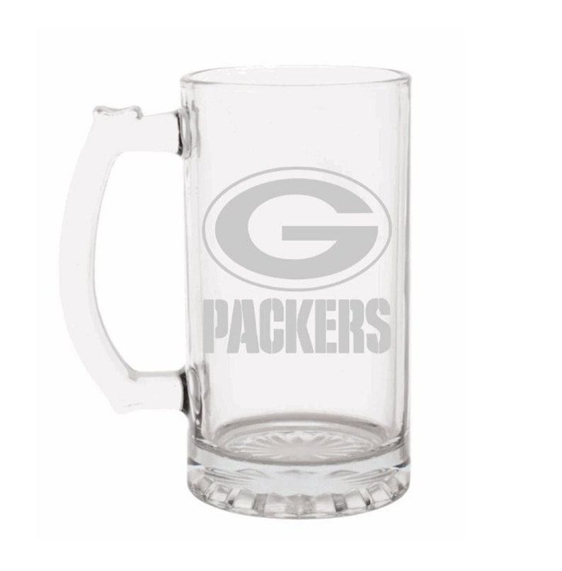 May include: Clear glass beer mug with a handle. The mug features the Green Bay Packers logo and the word "PACKERS" in gray. The mug has a decorative base.