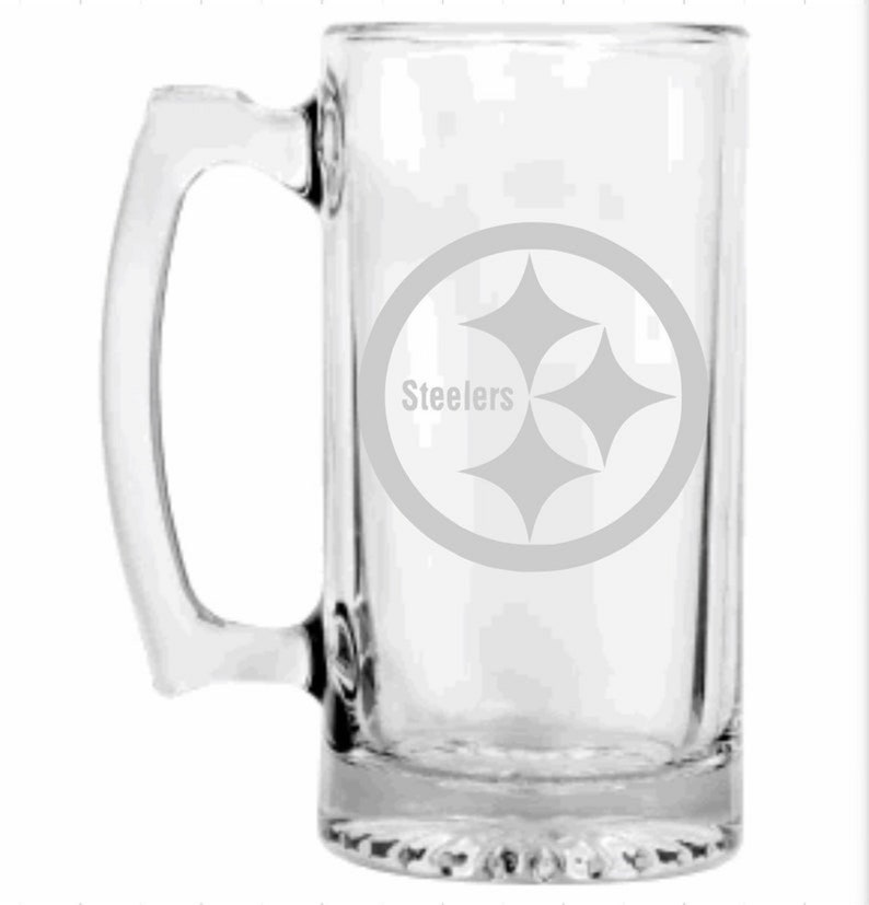 K&ouml;nnte beinhalten: Klarer Bierkrug aus Glas mit Henkel. Der Krug zeigt das Logo der Pittsburgh Steelers, einen grauen Kreis mit drei grauen Diamanten und dem Wort "Steelers" in Grau. Der Krug ist rechteckig mit einem dicken Boden.