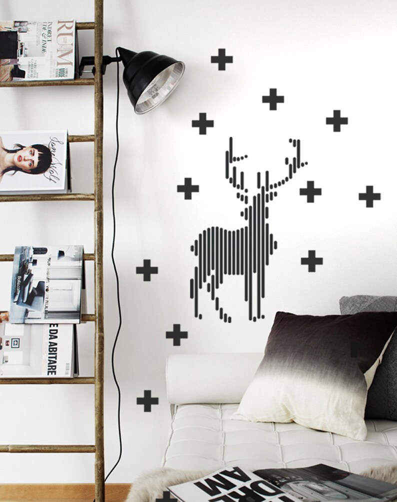 May include: Black and white striped deer silhouette wall decal with a plus sign pattern. The decal is on a white wall above a white sofa with a black and white throw pillow.