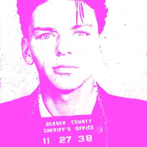 May include: A pink and white mugshot of a person with a chain around their neck. The mugshot has the text "BERGEN COUNTY SHERIFF'S OFFICE" and the numbers "11 27 38 42799".