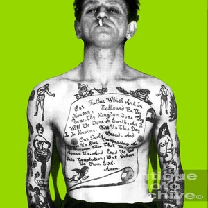 May include: A black and white photo of a man with a full-body tattoo. The tattoo includes a traditional style angel, a woman in a dress, a boxer, and a scroll with the Lord's Prayer. The man is smoking a cigarette and has a serious expression on his face.