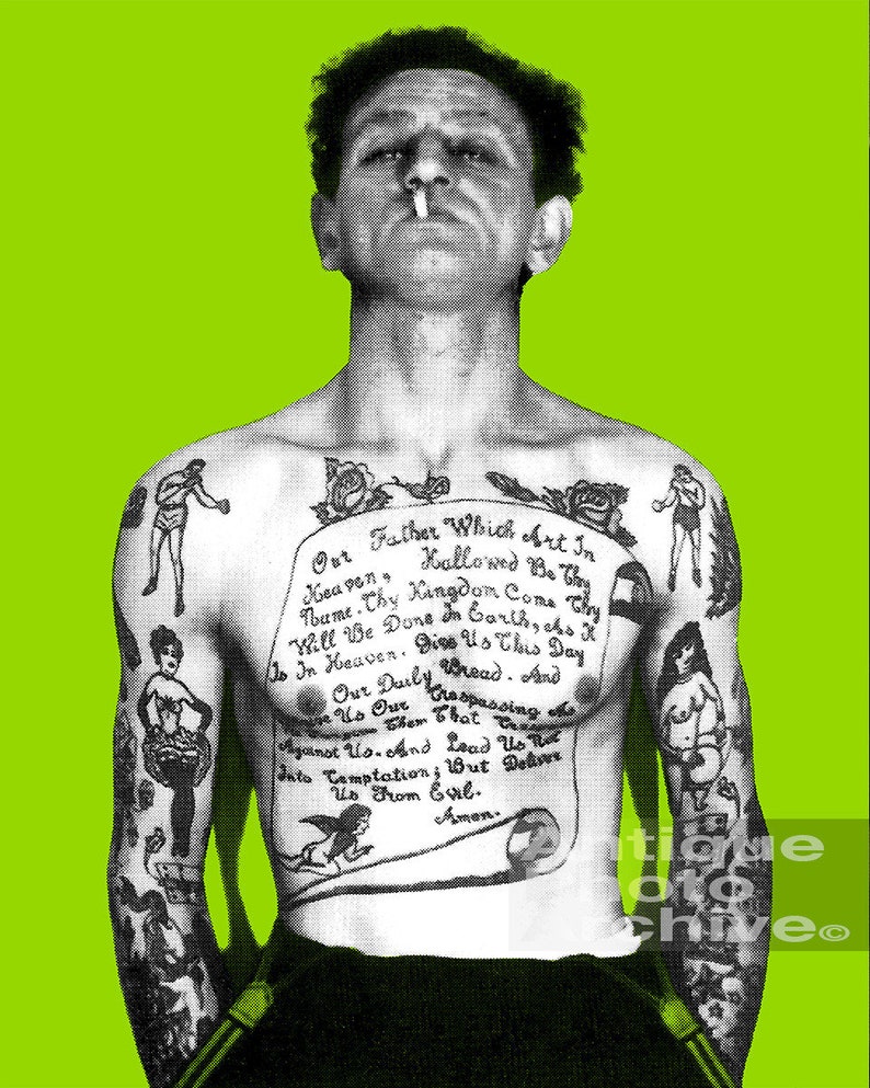 May include: A black and white photo of a man with a full-body tattoo. The tattoo includes a traditional style angel, a woman in a dress, a boxer, and a scroll with the Lord's Prayer. The man is smoking a cigarette and has a serious expression on his face.