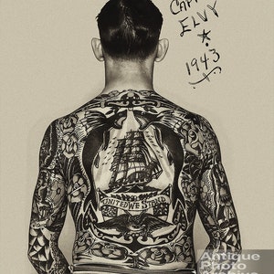 May include: A black and white photo of a man with a full back tattoo. The tattoo features a ship, an eagle, an anchor, and the words "United We Stand". The man's name, "Captain Elvy", and the year "1943" are written on the top right corner of the photo.