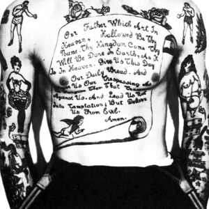 May include: A black and white photo of a person's torso with a large tattoo of the Lord's Prayer on their chest. The tattoo is surrounded by other smaller tattoos, including a woman holding a basket of flowers, a woman holding a ball, and a man boxing.