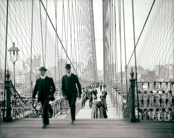 May include: A black and white photograph of people walking across the Brooklyn Bridge in New York City. The bridge is made of steel cables and has a long walkway. The people are dressed in clothing from the early 1900s.