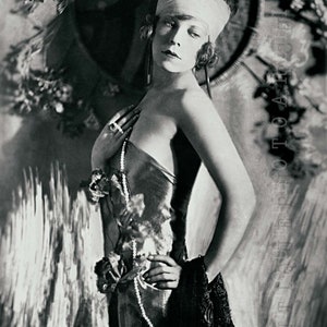 May include: A black and white portrait of a woman wearing a white turban, a beaded necklace, and a velvet dress. She is standing in front of a textured background.