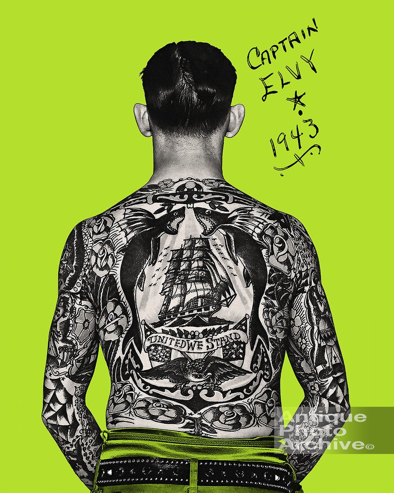 May include: A man with a full back tattoo of a ship, eagles, and an anchor. The tattoo includes the text "United We Stand". The man's back is facing the camera. The text "Captain Elvy 1943" is written in black marker on a green background.