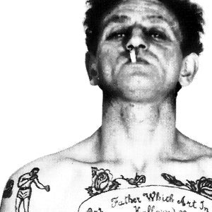 May include: Black and white photo of a man with a tattoo on his chest. The tattoo features a boxer, a rose, and the text "Our Father Which Art In Heaven."
