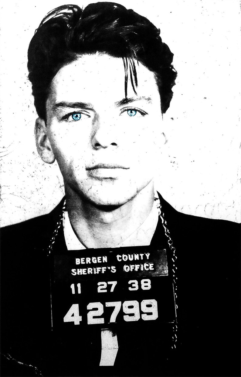 May include: Black and white mugshot of a man with blue eyes. The mugshot has the text "BERGEN COUNTY SHERIFF'S OFFICE" and the numbers "11 27 38 42799".