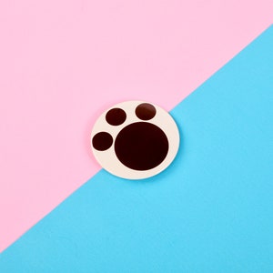 May include: A white circle with a brown paw print on a pink and blue background.