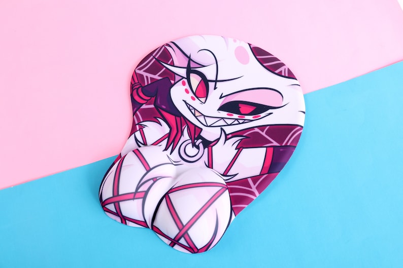 May include: Ergonomic mousepad with a cartoon character design. The mousepad features a white character with pink accents, a dark purple outfit, and a smiling expression. The background is pink and blue.