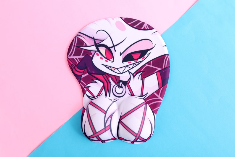 May include: A white and pink mousepad featuring a cartoon character with a mischievous grin and red eyes. The character has a spiderweb-like pattern on the head and torso, with pink accents. The mousepad has a wrist rest and is set against a pink and blue background.