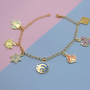 Könnte beinhalten: Ein goldenes Kettenarmband mit sieben Anhängern. Die Anhänger sind in verschiedenen Formen und Größen und haben verschiedene Farben, darunter Blau, Grün, Lila, Orange und Gelb.