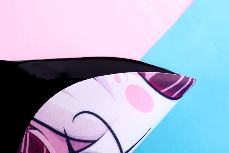 May include: A black, curved object with a white surface featuring a cartoon character design with pink and purple accents. The background is composed of pink and blue sections.