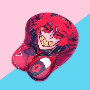 May include: Red and black mousepad with a cartoon image of a character with red hair and a large grin. The character has a large, white eye visible in the lower right corner of the image.