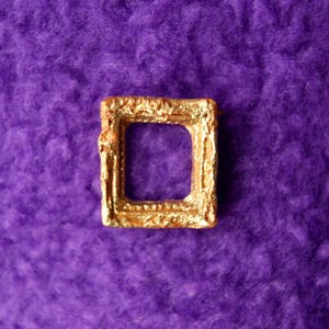 May include: A small, gold-colored picture frame with a simple, ornate design. The frame is empty and ready to hold a special photo or artwork.