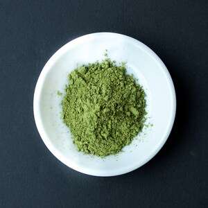 Puede incluir: Un bol de cer&aacute;mica blanca lleno de una generosa cantidad de polvo de matcha verde brillante.