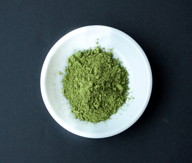 Puede incluir: Un bol de cer&aacute;mica blanca lleno de una generosa cantidad de polvo de matcha verde brillante.