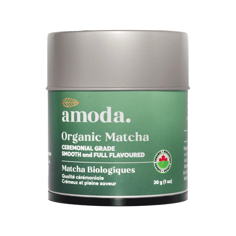 May include: A silver and green cylindrical container of organic matcha powder. The label reads "amoda. Organic Matcha Ceremonial Grade Smooth and Full Flavoured Matcha Biologiques Qualit&eacute; c&eacute;r&eacute;moniale Cr&eacute;meux et pleine saveur 30 g (1 oz)"