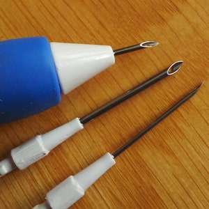 May include: A blue and white plastic tool with three different sized needles. The needles are used for punching holes in fabric.