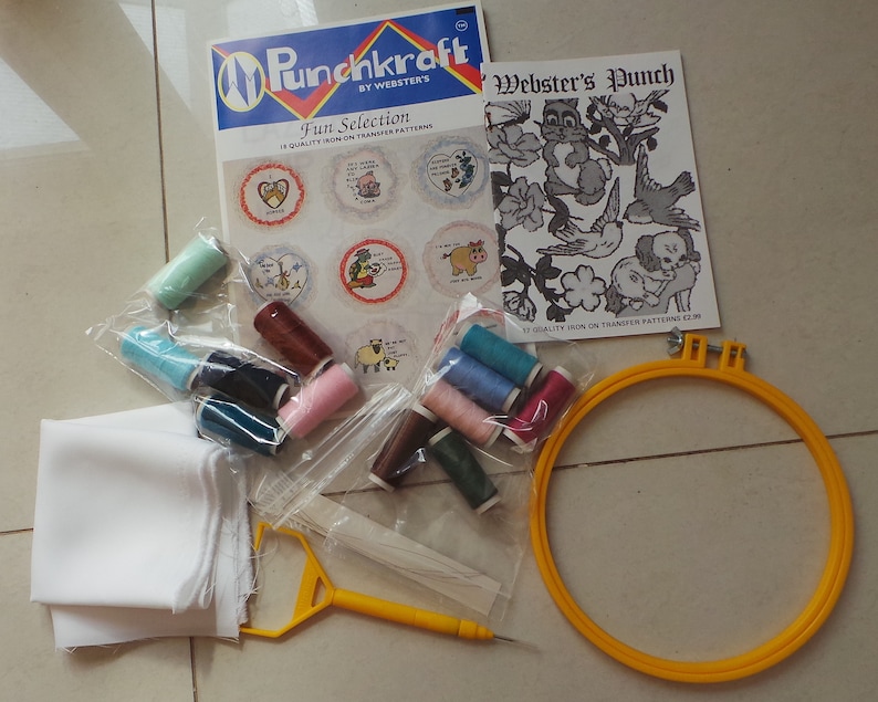 May include: Punchkraft Fun Selection embroidery kit with a white fabric square, a yellow embroidery hoop, and a variety of colored embroidery floss spools. The kit includes a pattern sheet with a cartoon illustration of a cat and a bird.
