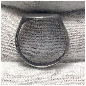 Pu&ograve; includere: Un anello a sigillo d'argento con una parte superiore liscia e arrotondata. L'anello &egrave; in metallo e ha un design semplice.