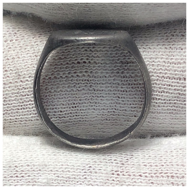 Pu&ograve; includere: Un anello a sigillo d'argento con una parte superiore liscia e arrotondata. L'anello &egrave; in metallo e ha un design semplice.