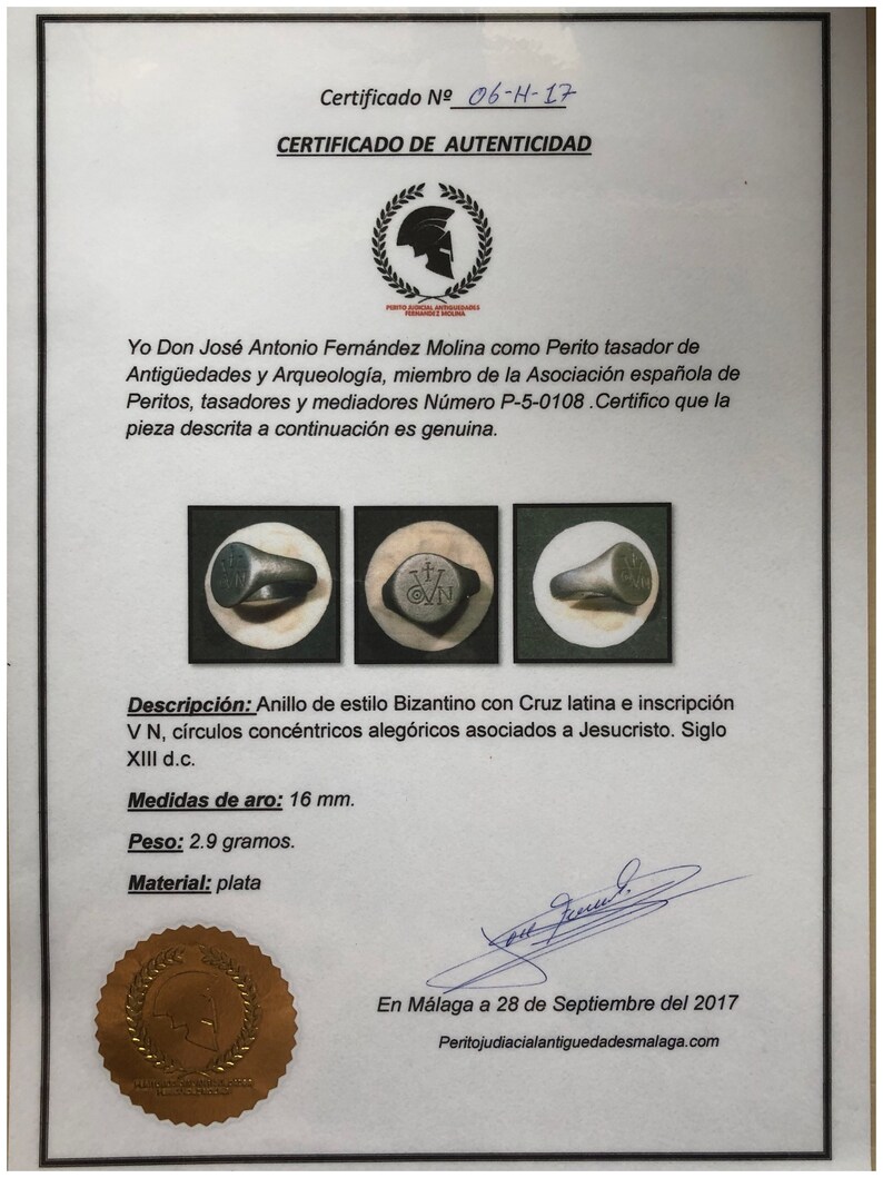 Pu&ograve; includere: Un certificato di autenticit&agrave; per un anello d'argento in stile bizantino. L'anello presenta una croce latina e l'iscrizione "VN" con cerchi concentrici. L'anello ha un diametro di 16 mm e pesa 2,9 grammi. Il certificato &egrave; datato 28 settembre 2017.