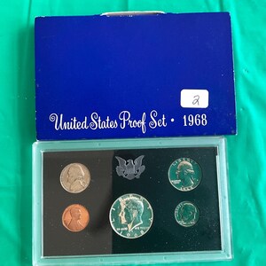May include: A 1968 United States Proof Set in a blue box. The set includes various coins, including a silver half dollar, a quarter, a dime, a nickel, and a penny. The box is labeled "United States Proof Set" and the year.