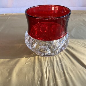 May include: A clear glass bowl with a red glass top. The bowl has a textured, starburst pattern.