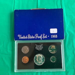 May include: A 1968 United States Proof Set in a blue box. The set includes various coins, such as a penny, nickel, dime, quarter, and half dollar, displayed in a clear plastic case. The box is labeled "United States Proof Set - 1968".