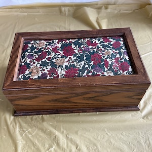 May include: A wooden storage box with a floral patterned fabric top. The box is brown with a dark wood grain.